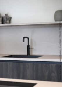 Een keuken met kasten is uitgevoerd in decoratief plaatmateriaal met het effect van verbrand hout, de S171 Bruciato van Cleaf. Het werkblad en de spatwand geven de beleving van natuursteen in decoratief plaatmateriaal FC36 Concreta van Cleaf.