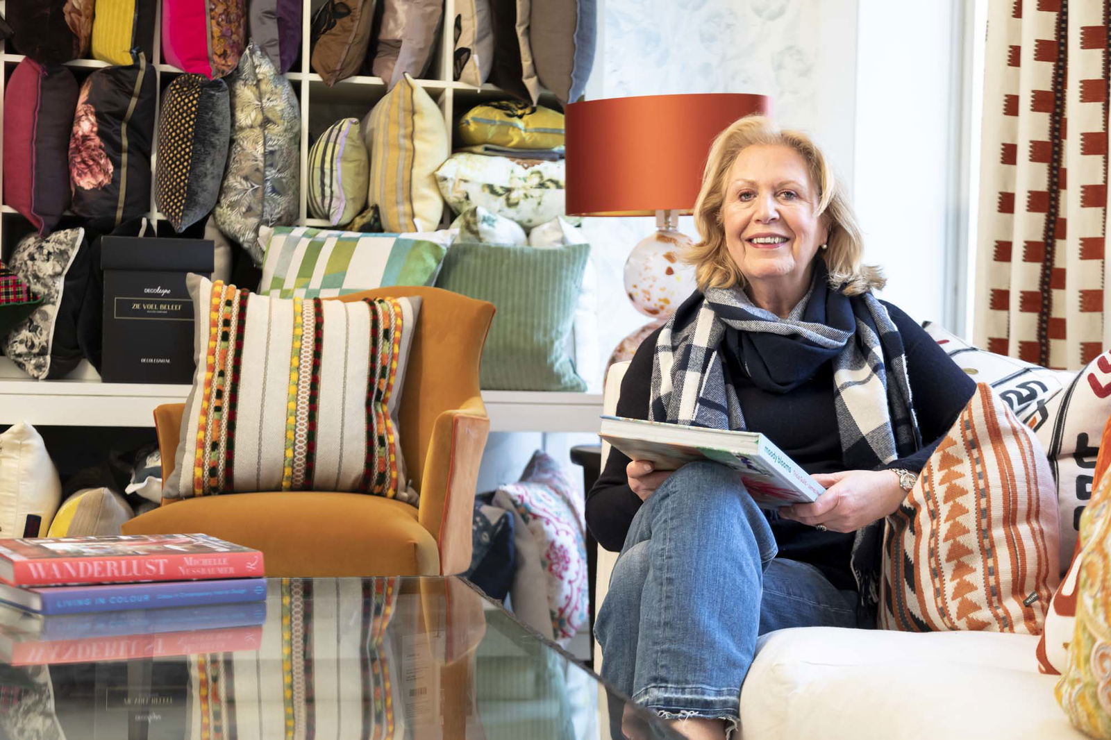 Wilhelmine van Aerssen zit op een bank met kleurrijke stoffen en boek in hand