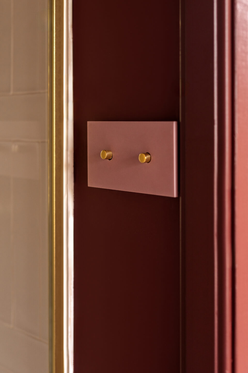 Roze lichtschakelaars gemaakt in solid surface DM1032 Bohemian van Durasein op rode muur